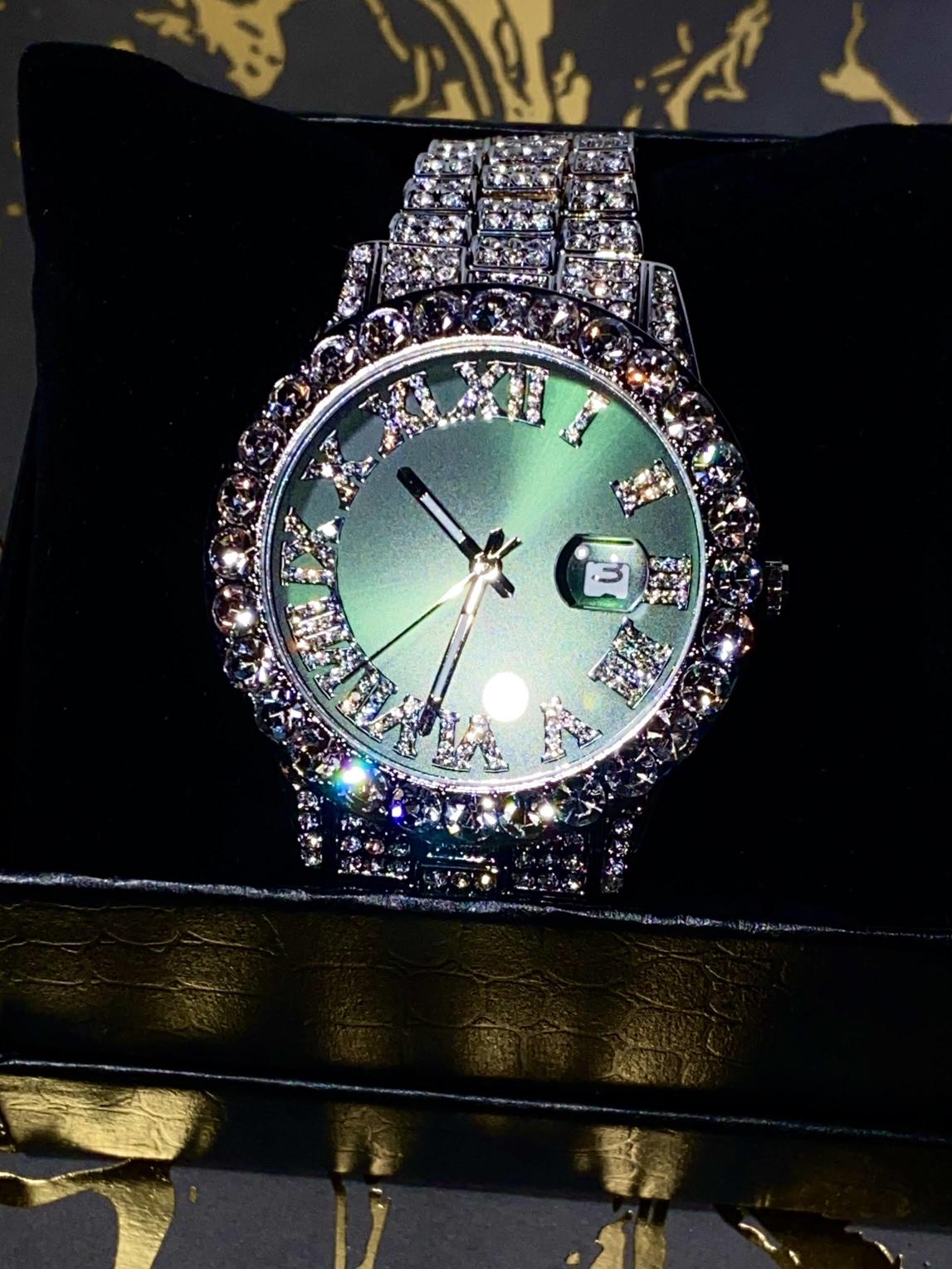 Silver iced-out watch with emerald green dial, Roman numerals, and diamond bracelet – luxury streetwear timepiece