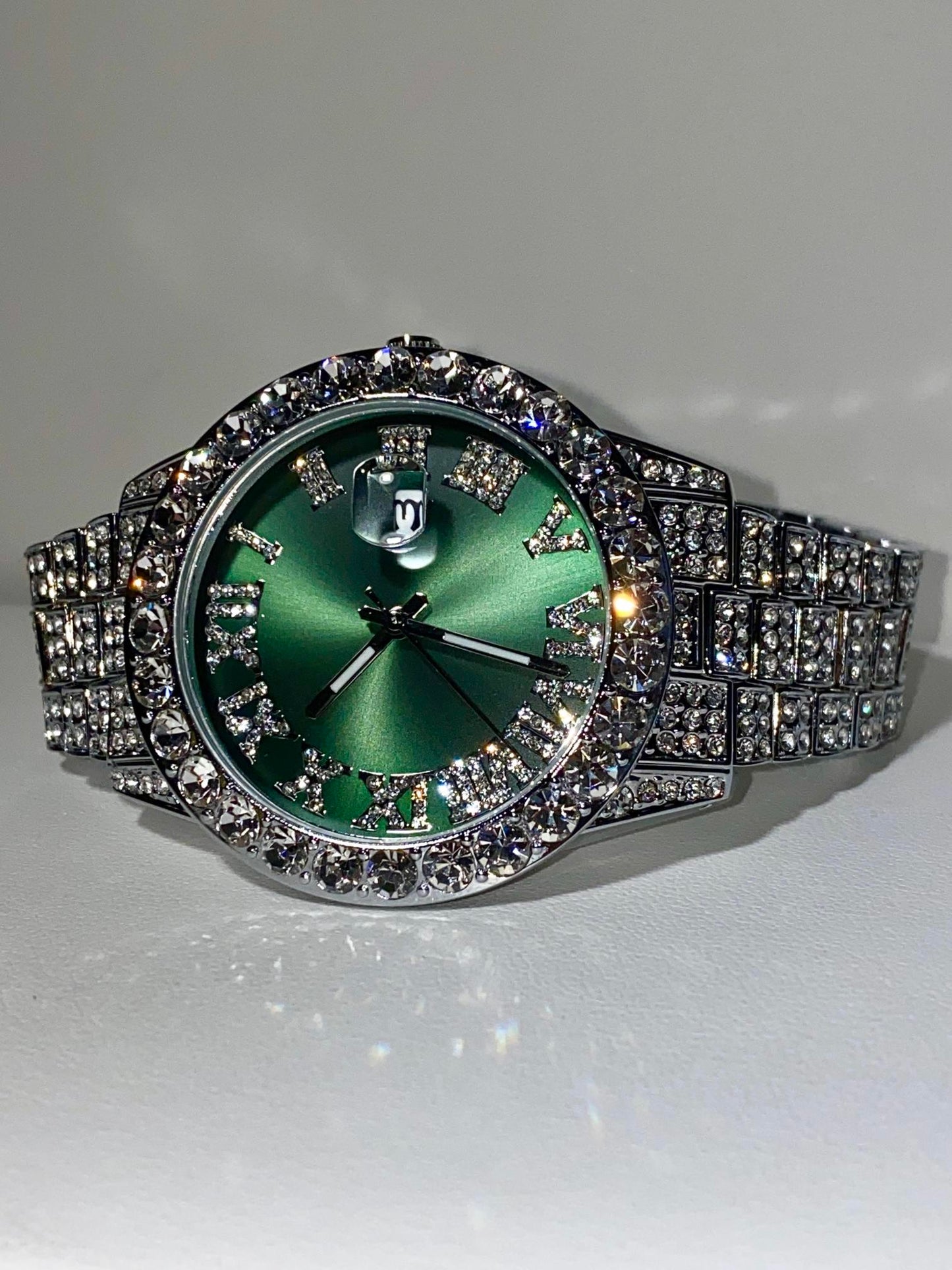 Silver iced-out watch with emerald green dial, Roman numerals, and diamond bracelet – luxury streetwear timepiece