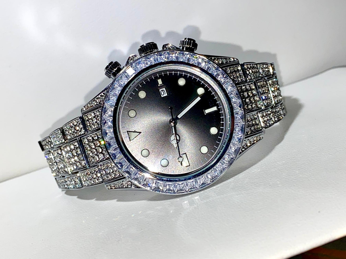 Silver iced chronograph watch with black dial displayed on white ceramic cuff – ShadowFlex 42MM by Time Flex
