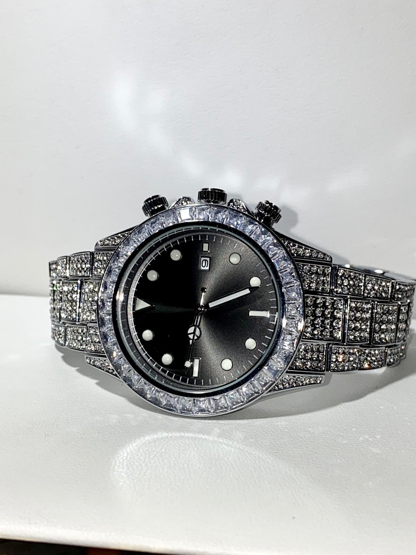 Silver iced chronograph watch with black dial displayed on white ceramic cuff – ShadowFlex 42MM by Time Flex